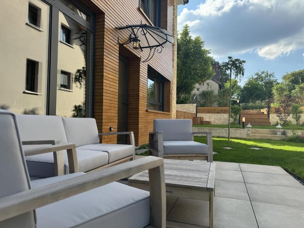 Une terrasse avec des meubles d’extérieur, un mur en bois et une vue sur un immeuble doté de fenêtres.