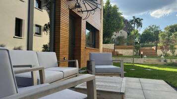 Une terrasse avec des meubles d’extérieur, un mur en bois et une vue sur un immeuble doté de fenêtres.