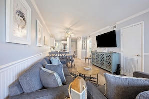 A modern living room with a sofa, coffee table, and a TV mounted on the wall. - Minutes to the beach,heatedoutdoor pool,onsite beach bar &grill, pool bar &grill (Hilton Head Island)