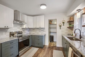 A modern kitchen with white cabinets, a stainless steel range, and a granite countertop.