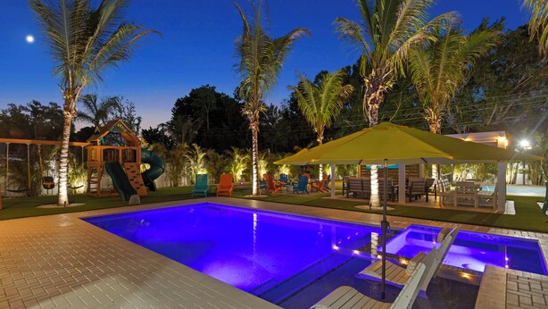 Ein Swimmingpool mit Rutsche, Palmen und Sitzgelegenheiten im Freien.