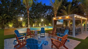 Eine Terrassengruppe im Freien mit Adirondack-Stühlen, einer Feuerstelle und einem Poolbereich.
