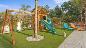Ein Spielplatz mit Schaukeln, einer Rutsche und Sitzgelegenheiten.