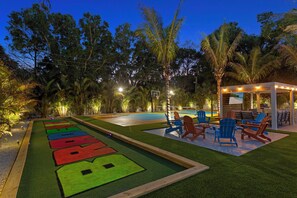 Ein Poolbereich mit Shuffleboardplatz, Sitzgelegenheiten im Freien und einer überdachten Terrasse.