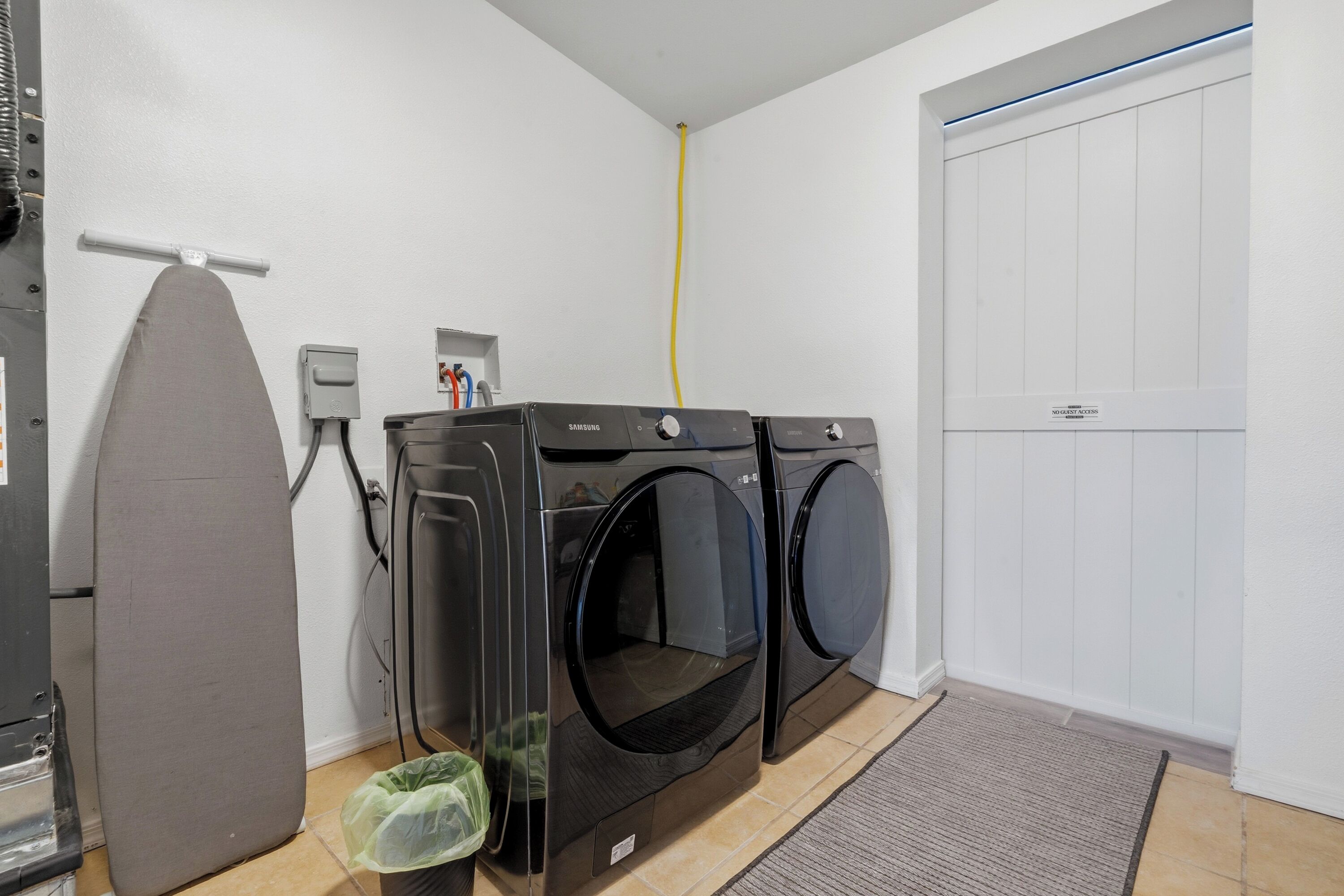 A laundry room with a dryer, washing machine, and ironing board.