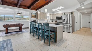 Una cocina moderna con barra, ventanas amplias y un techo alto con vigas a la vista.