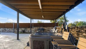 Un espacio al aire libre cubierto con un jacuzzi, bancos de madera y una pared de piedra.