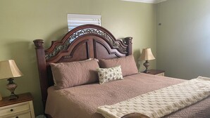 A bed with a wooden headboard, two bedside tables with lamps, and a nightstand with drawers.