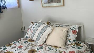 Een bed met een quilt met bloemenprint, een ingelijst schilderij en twee wandlampen.