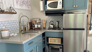 A kitchen with blue cabinetry, a stainless steel refrigerator, a microwave, and a gas stove.