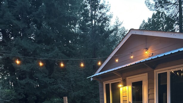 A wooden deck with chairs, a grill, and string lights.