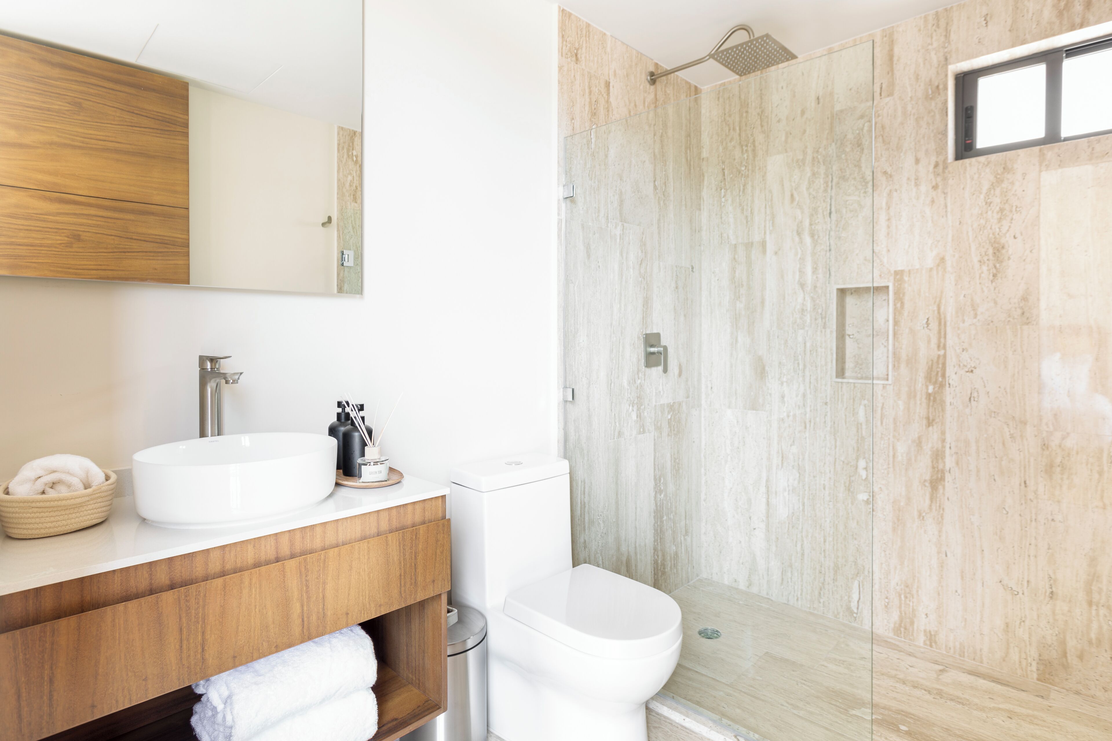 Ein Badezimmer mit weißem Waschbecken, Holz-Waschtisch und einer Duschkabine.