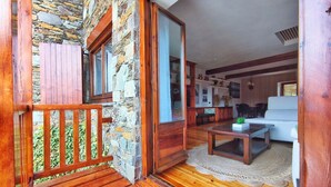 A wooden deck with a stone wall, a wooden bench, a coffee table, and a sofa in the background. - House in La Cerdanya, Ger. Surrounded by nature (La Pleta de Saga)