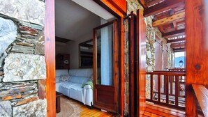 A wooden balcony with stone walls, a white sofa, and a view of the outdoors. - House in La Cerdanya, Ger. Surrounded by nature (La Pleta de Saga)