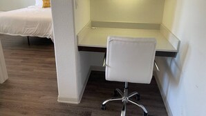 Ein Schlafzimmer mit Bett, Schreibtisch mit Stuhl und Schrank.