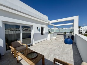 Eine moderne Dachterrasse mit Sitzgelegenheit, einer kleinen Bar und Blick auf die Stadt.