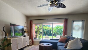 Una sala de estar con un sofá, una mesa de centro, un televisor y un ventilador de techo.