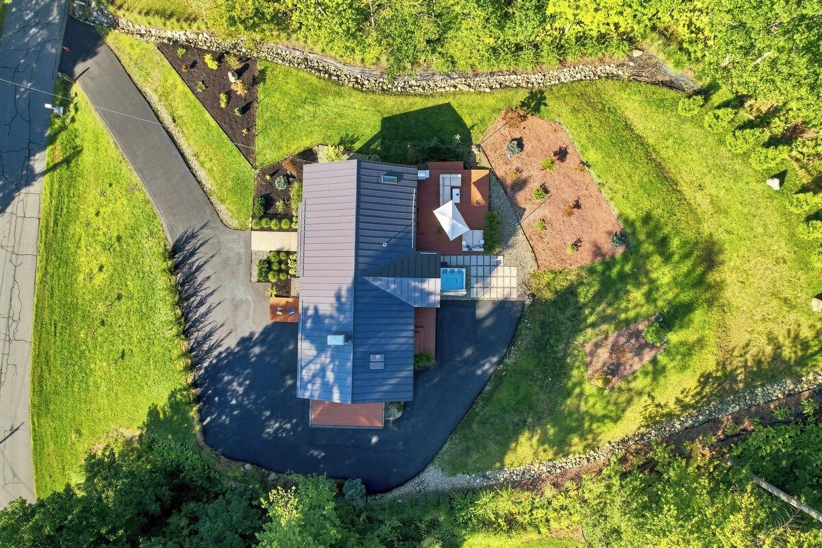 A modern house with a sloped roof, a covered patio, and a driveway.