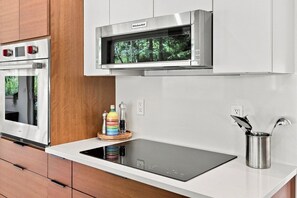 A modern kitchen with a built-in oven, a microwave, and a sleek induction cooktop. - Hanover Luxury MCM Retreat | Dartmouth Graduation (Hanover)