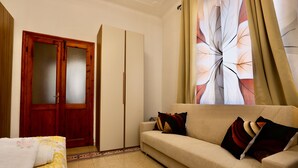 A room with a bed, a sofa, a wardrobe, and a large window with curtains. - Alex's House La Spezia Migliarina 10 min from Migliarina Station (La Spezia)