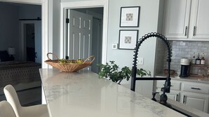 Una cocina con encimera de mármol, un grifo negro y una cesta de fruta.