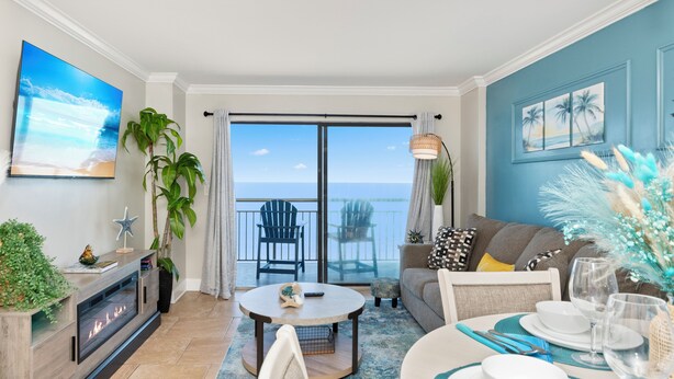 A modern living room with a fireplace, a dining area with a table set for two, and a balcony with a view of the sea. - Direct Oceanfront Views  2BR 2B Condo  Private Balcony  Sleeps 6 (Myrtle Beach)