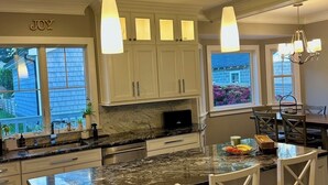 Una cocina moderna con una isla grande, armarios blancos e iluminación colgante.
