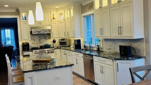 Una cocina amplia con armarios blancos, encimera de mármol y una isla central.
