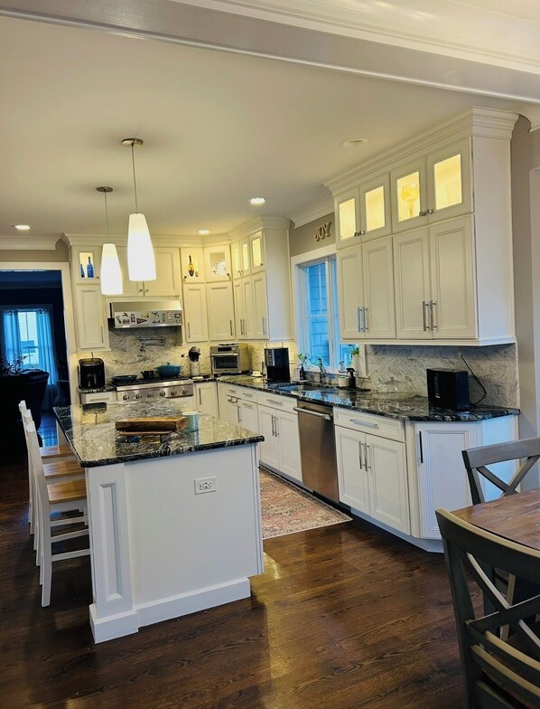 A spacious kitchen with white cabinets, a marble countertop, and a central island. - Luxury Coastal Retreat ✨ 5 min to Beach,Sleeps 10,BBQ + Patio (Long Branch)