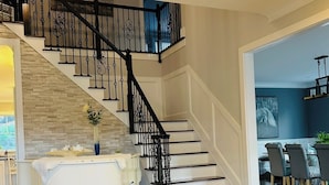 Un interior moderno con una escalera, un comedor y vistas al exterior.