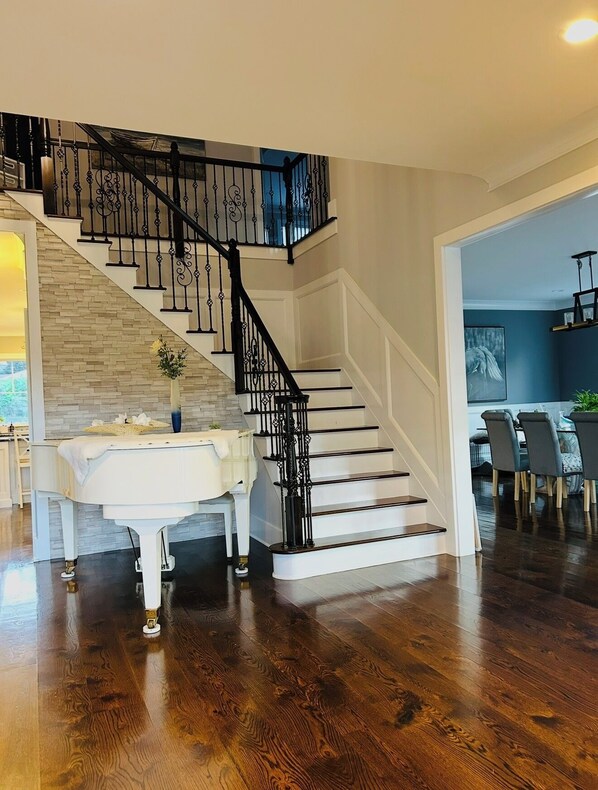 A modern interior with a staircase, a dining area, and a view of the outdoors. - Luxury Coastal Retreat ✨ 5 min to Beach,Sleeps 10,BBQ + Patio (Long Branch)