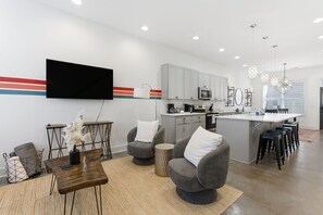 A modern kitchen with white cabinets, a central island, and bar stools. - Modern 3BR w/ Rooftop • 10 Min to Broadway (Nashville)