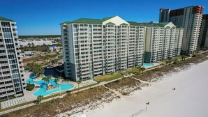 Ein Hochhaus-Hotel mit mehreren Balkonen, einem Pool und Blick auf den Strand.