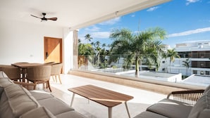 A modern living room with a sofa, a wooden table, and wicker chairs. - Penthouse 3BR Ocean View & Pool | Sol de Arena F7 (Las Terrenas)