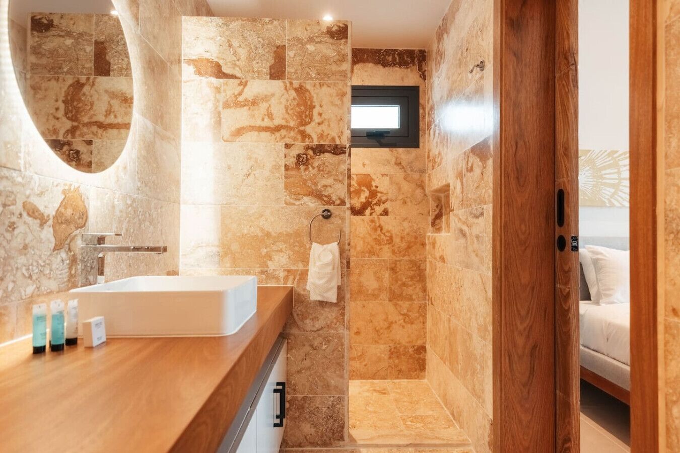 A modern bathroom with a wooden vanity, a large mirror, and a shower area.