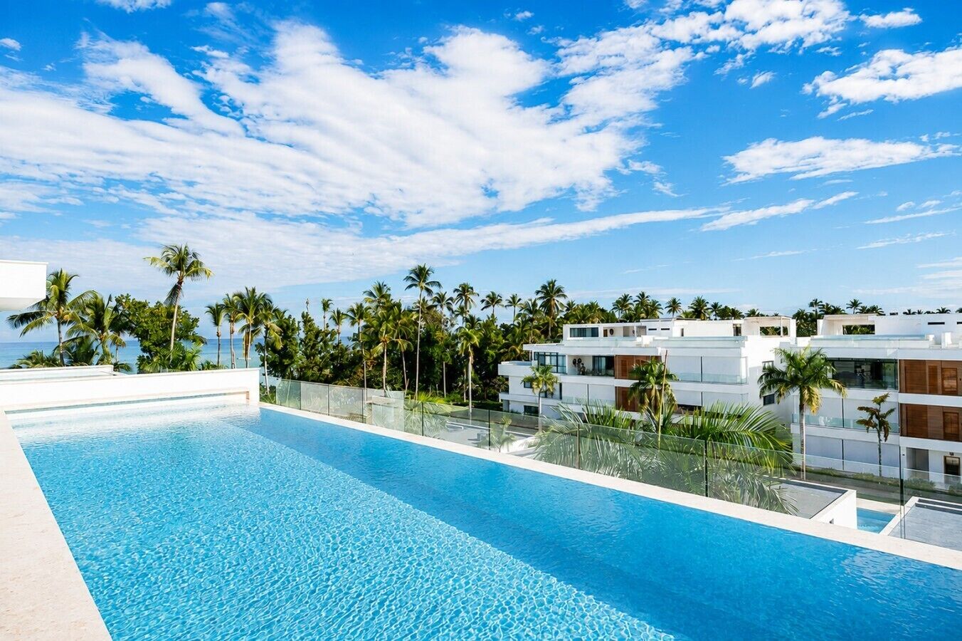 Um hotel moderno com piscina, palmeiras e um céu azul límpido.