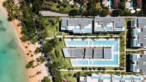 An aerial view of a resort with multiple buildings, a large swimming pool, and a beach. - Penthouse 3BR Ocean View & Pool | Sol de Arena F7 (Las Terrenas)
