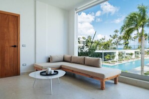 Ein modernes Wohnzimmer mit großem Fenster, Holztür und Blick auf einen Pool.