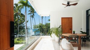 A balcony with a glass railing, a wooden door, and a ceiling fan. - 2BR Partial Ocean View on Beach | Sol de Arena A5 (Las Terrenas)