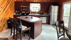 Une cuisine de style rustique, avec des murs en bois, un îlot central et un réfrigérateur.