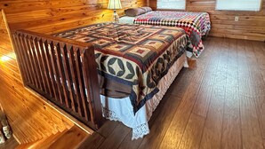 Une chambre à coucher dans une cabane en bois, avec un lit, une table de chevet, une lampe et un ventilateur de plafond.
