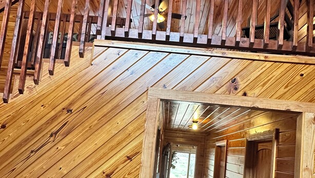 Un intérieur en bois avec un escalier, un couloir et une pancarte sur laquelle on peut lire : « Chez soi, quel bonheur ! »