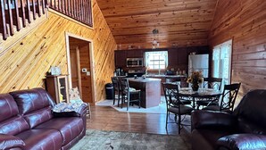 L’intérieur d’un chalet en bois comprend un salon, un coin repas, une cuisine et une chambre située en mezzanine.