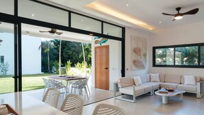 Una sala de estar moderna con sofá, mesa de centro y comedor con sillas.