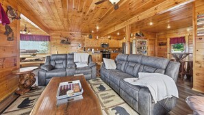 A log cabin interior with a dining area, two sofas, a coffee table, a ceiling fan, and a kitchen area. - Million Dollar Majestic View with best views around!!!! (Sevierville)
