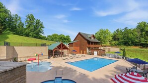 A pool area with a wooden cabin, lounge chairs, and umbrellas. - Million Dollar Majestic View with best views around!!!! (Sevierville)