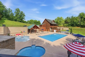 A pool area with a wooden cabin, lounge chairs, and umbrellas. - Million Dollar Majestic View with best views around!!!! (Sevierville)