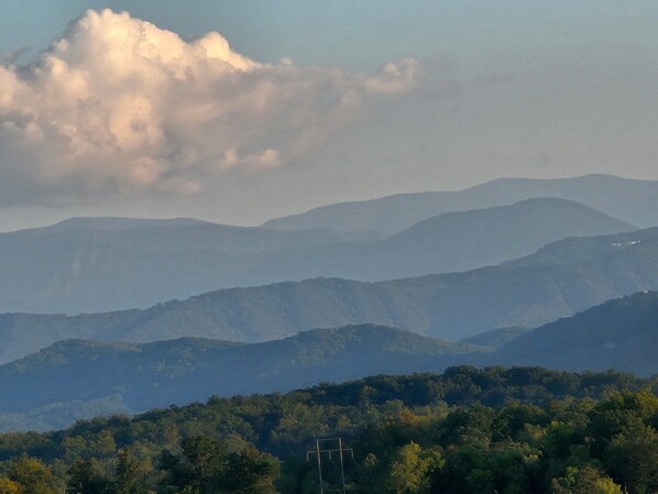 Paisagem montanhosa sob um céu claro e uma formação de nuvens notável.