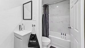 Un baño con lavamanos, inodoro y bañera blancos.