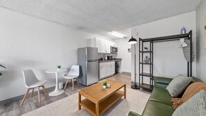 Un espacio habitable compacto con kitchenette, comedor y zona de estar.